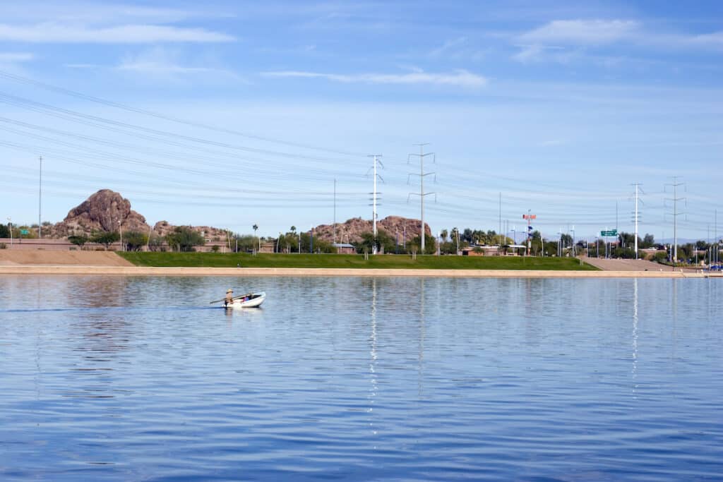 A small fishing boat moves along the surface of Tempe Town Lake near downtown Tempe and Arizona State University.