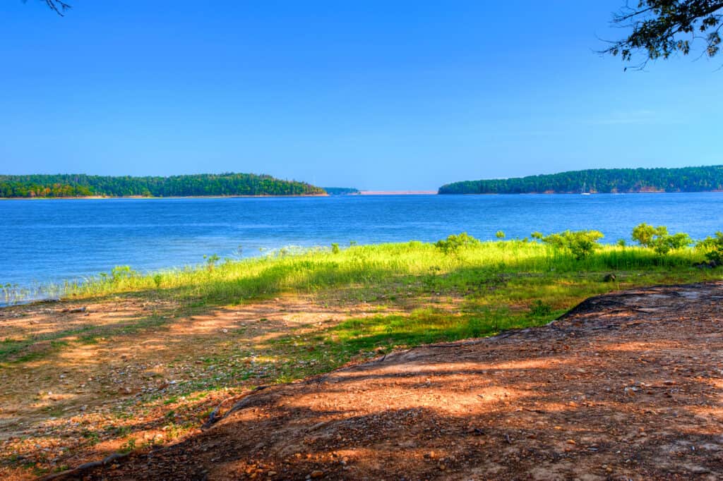 Blue water of DeGray Lake in the Ouachita Mountains with forest in the background.