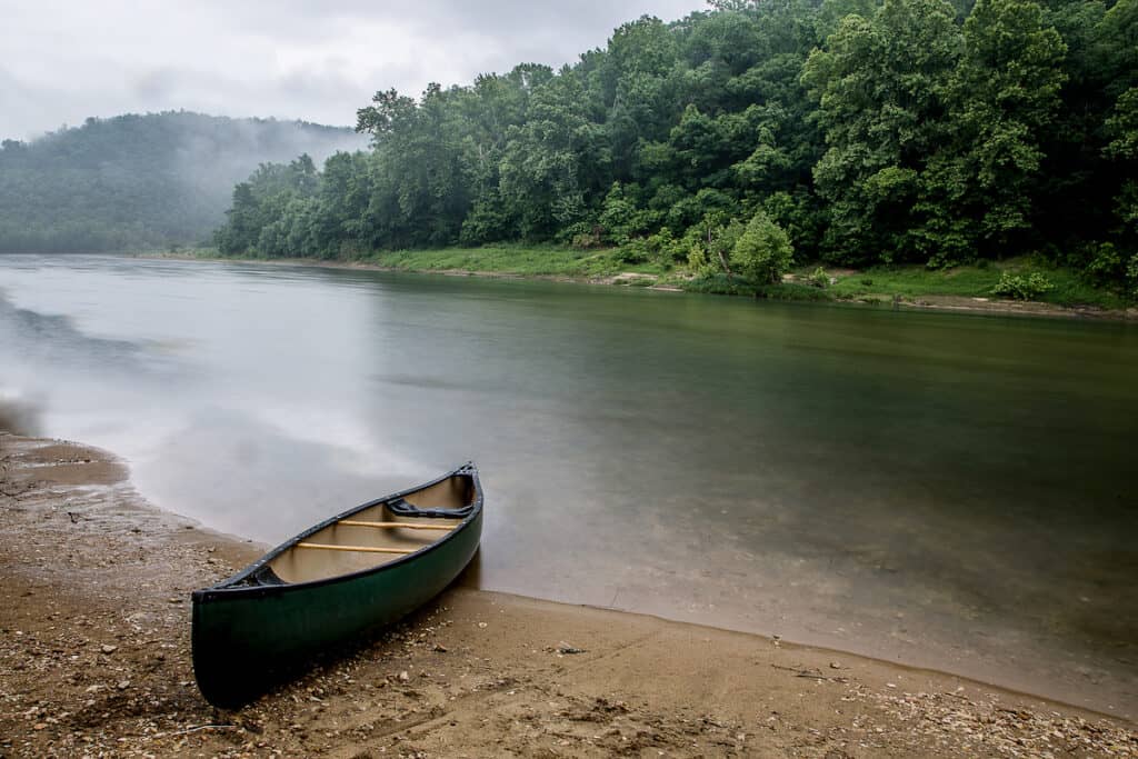 A canoe sits on the bank of the Buffalo River, one of the best smallmouth bass fishing spots in Arkansas.