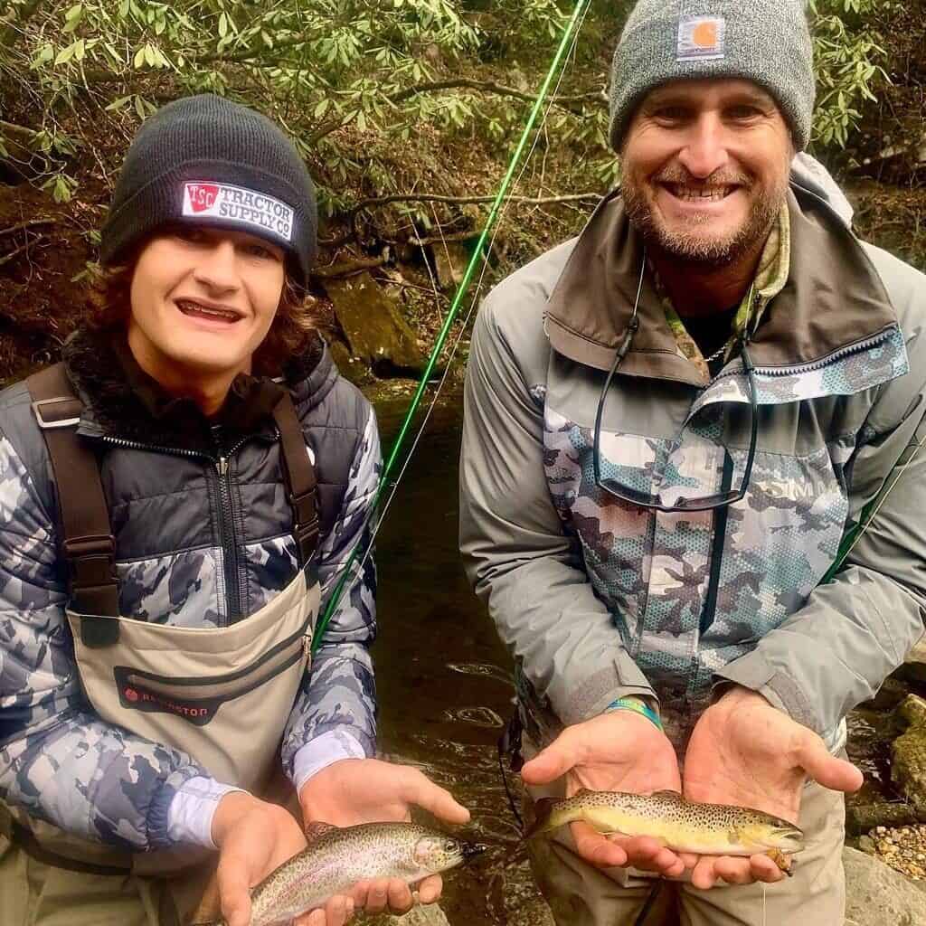 Two smiling fly anglers each hold trout in their palms, which they caught fishing Rock Creek in North Georgia.