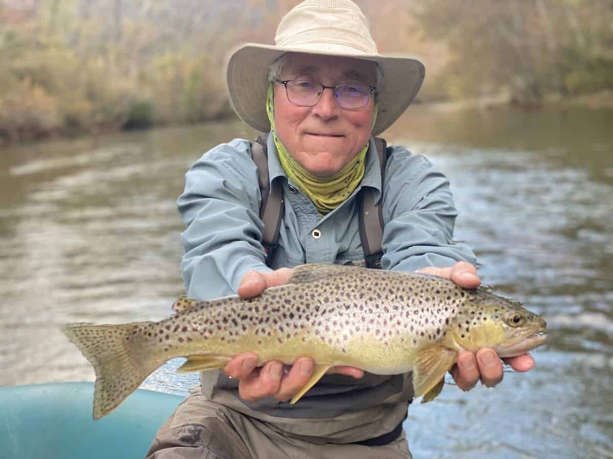 An angler holds a large brown trout with both hands while fishing on the Jackson River in Virginia.