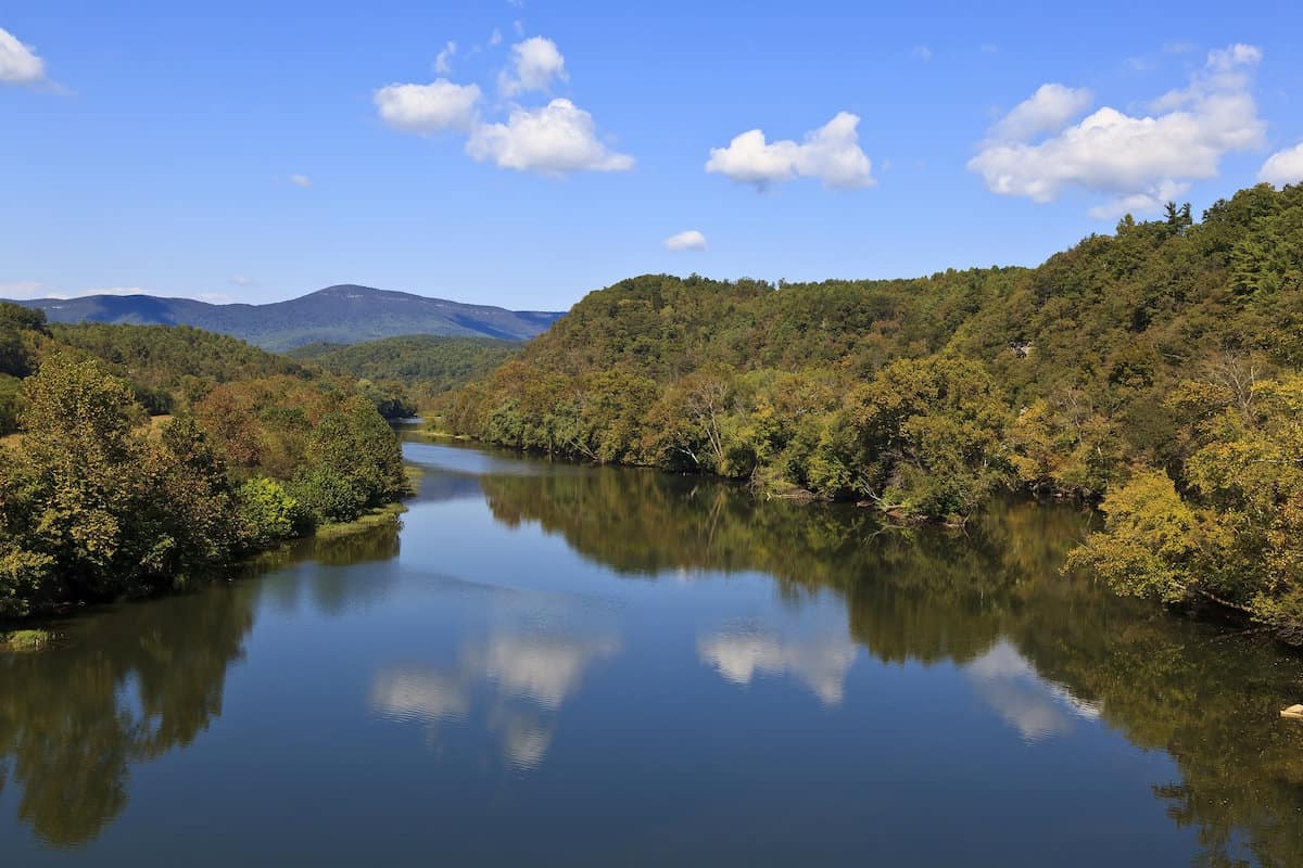 Scenic view of a serene section of the tree-lined James River, one of Virginia's best catfishing spots.