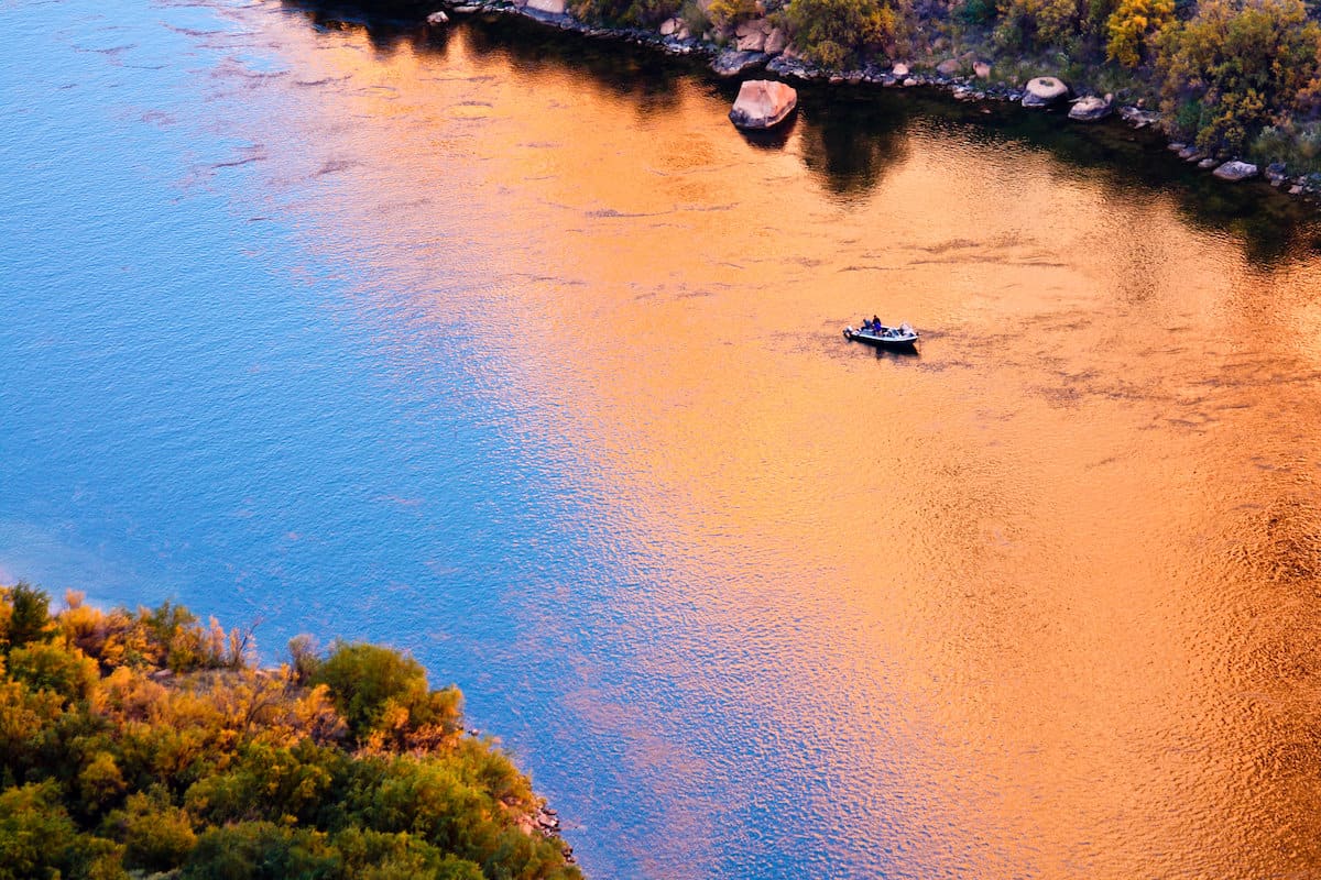 A fishing floats on the Colorado River in Northern Arizona as the orange sunlight reflects on the water.