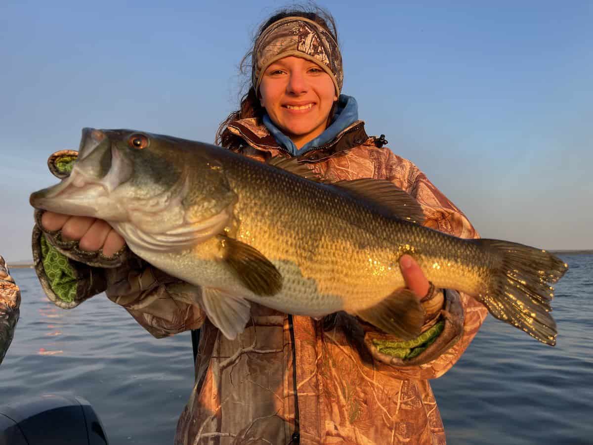 A young woman holds a trophy largemouth bass she caught in Lake Champlain.