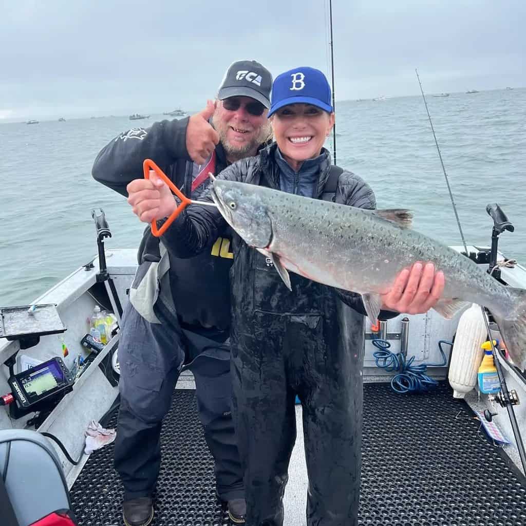 Fishing guide behind woman holding a large chinook salmon caught in the Buoy 10 area near Astoria, Oregon.