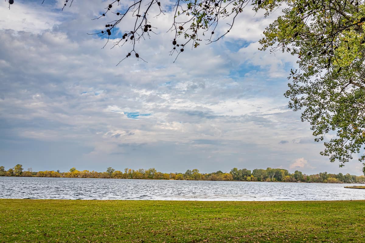 Scenic photo of Misery Bay on Presque Isle Bay, with grass and trees on the foreground shore.