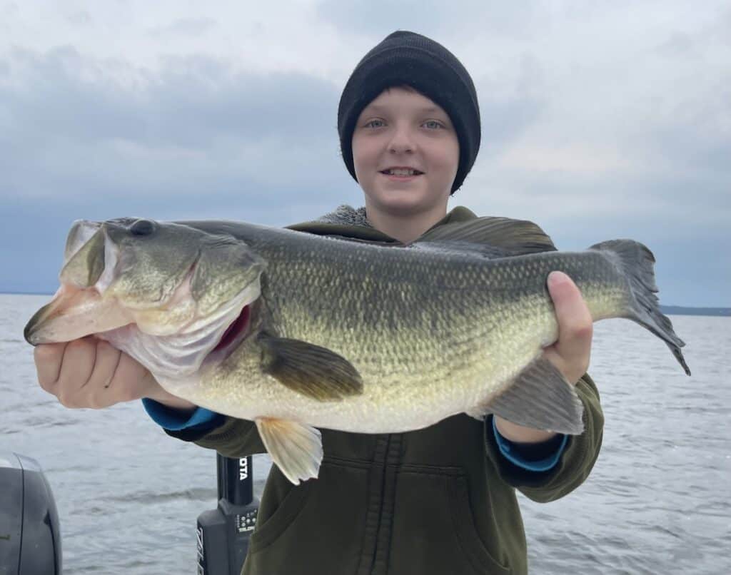 A boy holds a trophy largemouth bass caught on Lake Champlain.