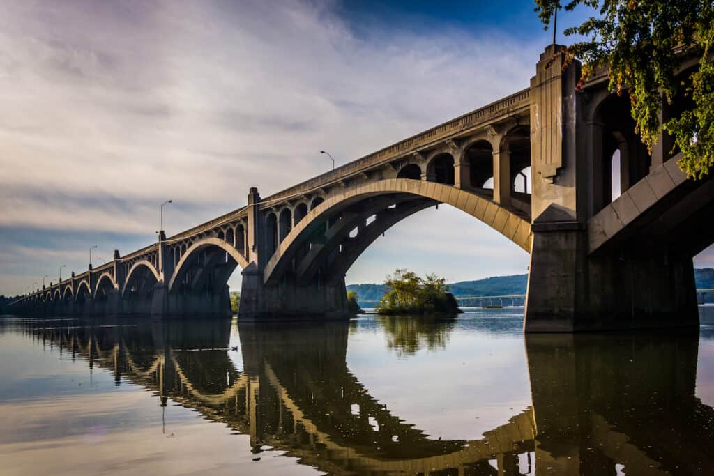 A rocky island shows between the arches of the Veterans Memorial Bridge on the Susquehanna River, showcasing excellent fishing structures.
