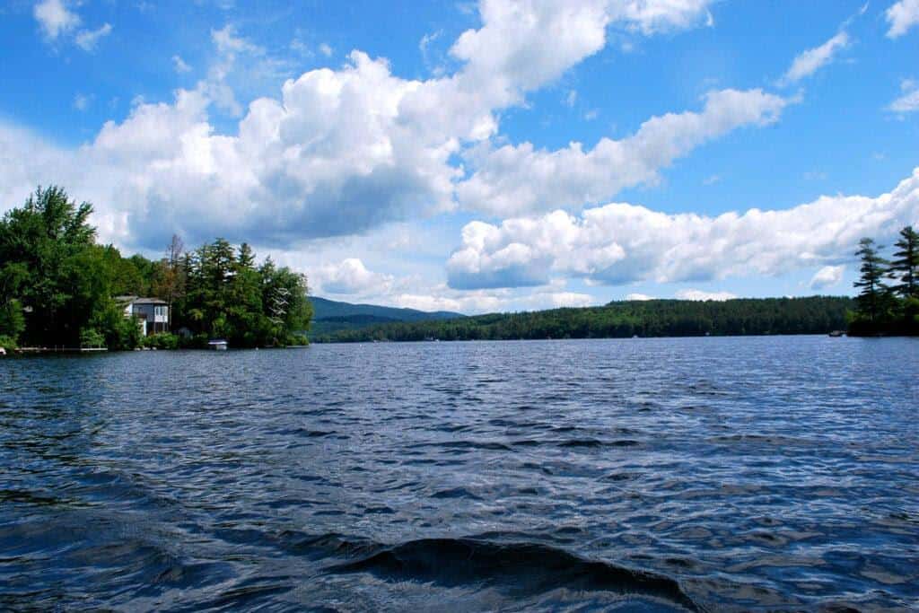 Photo showing water and forested shoreline and a house at Lake Winnipesaukee.