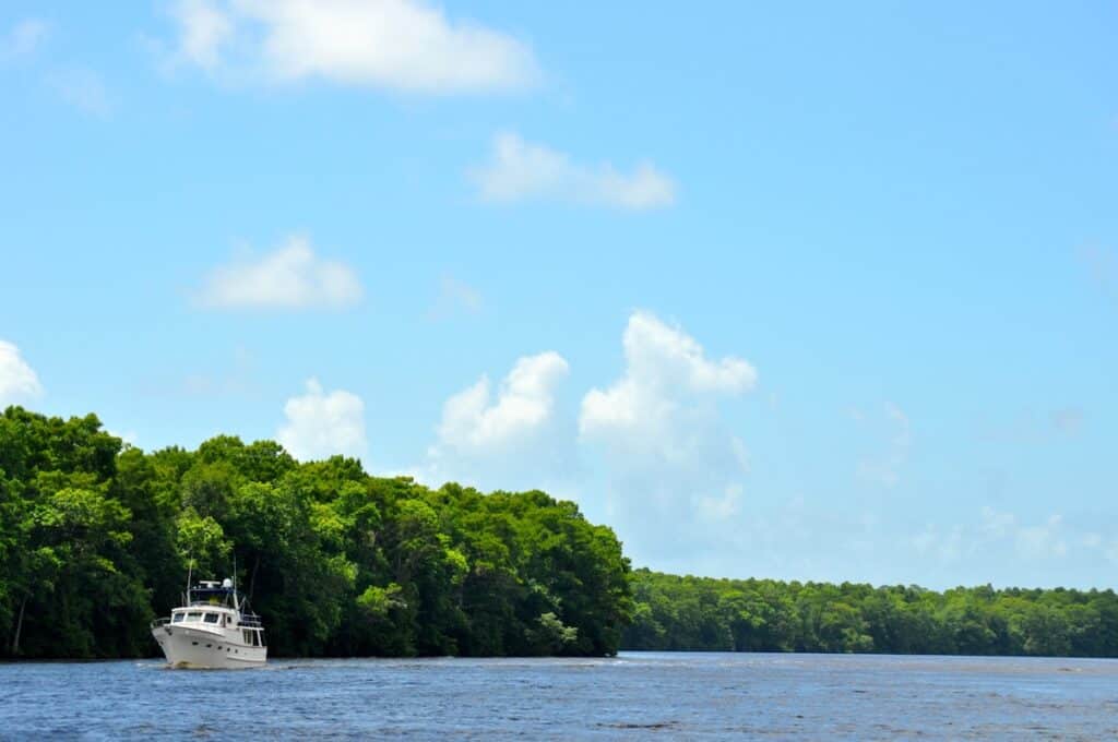 Boat motoring on the Ohio River's blue water with lush trees in the background.