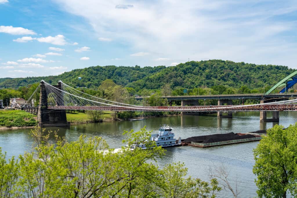 Old suspension bridge carrying the National Road above a coal barge on the Ohio river in Wheeling, West Virginia.