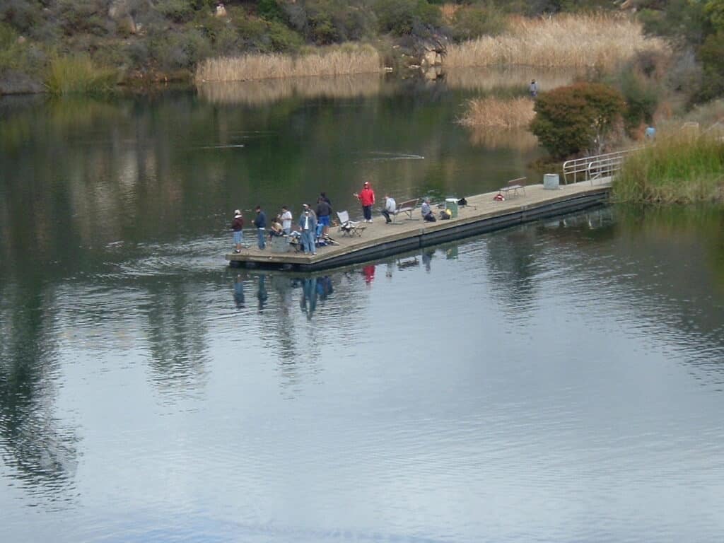Anglers sit and stand while fishing from a pier at Dixon Lake, hoping to catch trout, bass, panfish or catfish.