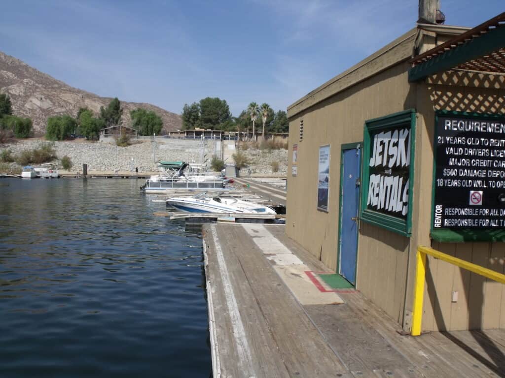 The marina at Lake Perris State Park with rental fishing boats and private watercraft mooring along docks. 