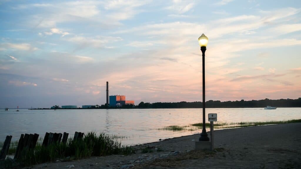 Evening photo of Calf Pasture Beach with a fishing boat on the water of Long Island Sound along the Connecticut shoreline.