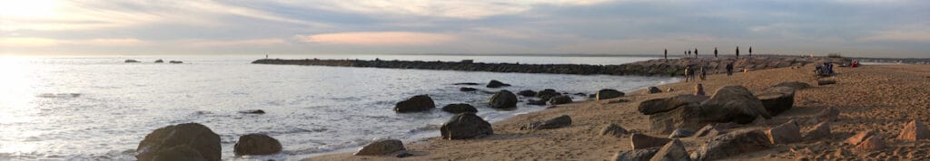 Wide panoramic of Hammonasset Beach and jetty sticking into Long Island Sound at sunset, a great time and place for striper fishing.