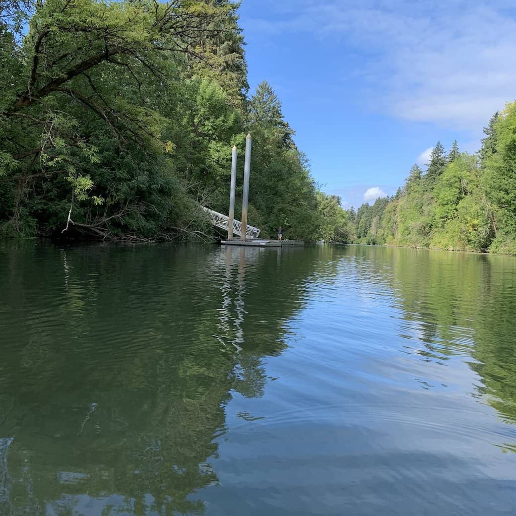 A boy fishing from a dock on the placid and tree-lined Tualatin River in Oregon.