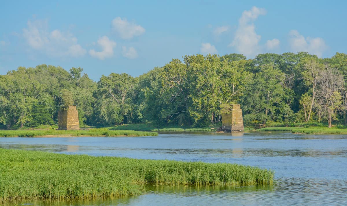 The Kankakee River flows slowly between shoreline grasses and trees in Kakakee River State Park, an excellent fishing spot in Indiana.