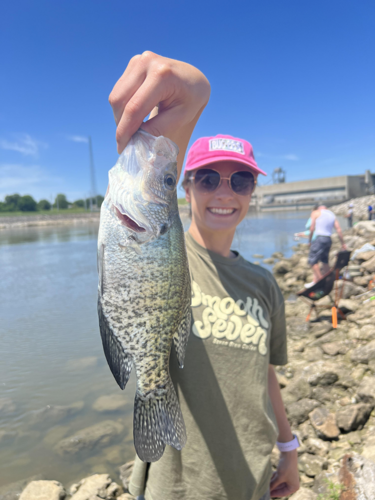 A smiling woman holds up a crappie she caught fishing at Truman Lake in Missouri.