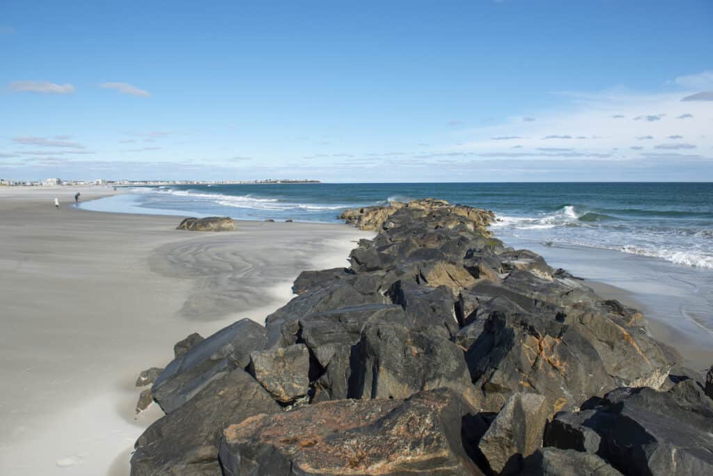 Rocks reach into the surf at Hampton Beach, a good striper fishing area in New Hampshire.