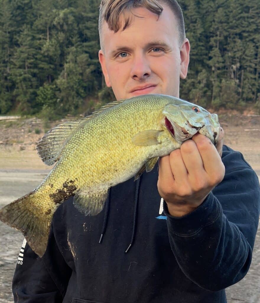 Man holds up smallmouth bass he caught fishing in Lookout Point Lake.