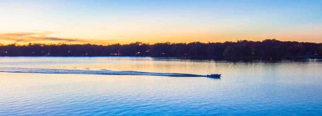 A boat motors across Lake Wylie leaving a wake at sunset, a great time to fish this reservoir on the North Carolina and South Carolina border.