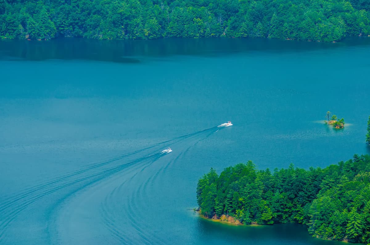 White boats motor across the blue water of Lake Jocassee, an excellent fishing spot in the South Carolina mountains.