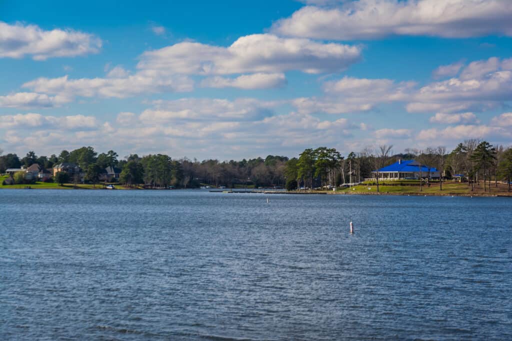 Lake Murray scenic photo with blue water in the foreground and a blue-roofed building and boat docks in the distance.