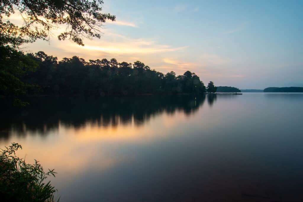 Anglers in a boat in the distance on the calm surface of Lake Hartwell are likely to catch catfish as the sky darkens.