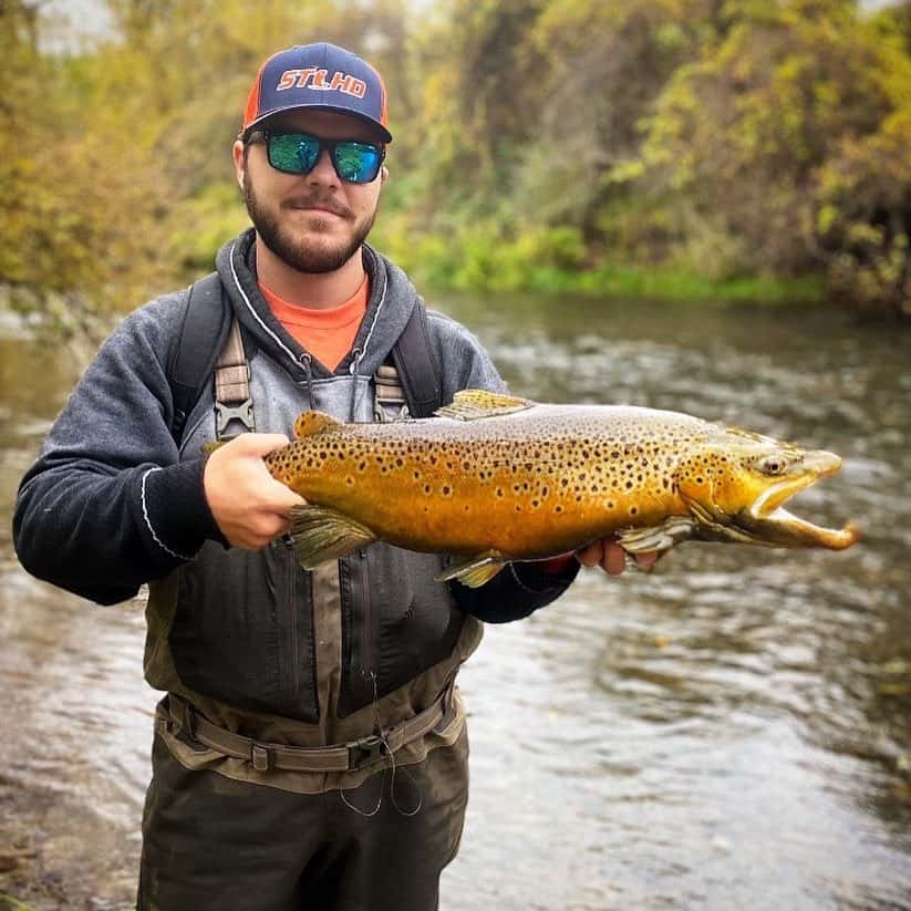 Josh Crandall holding a giant brown trout he caught fishing in a New York stream.