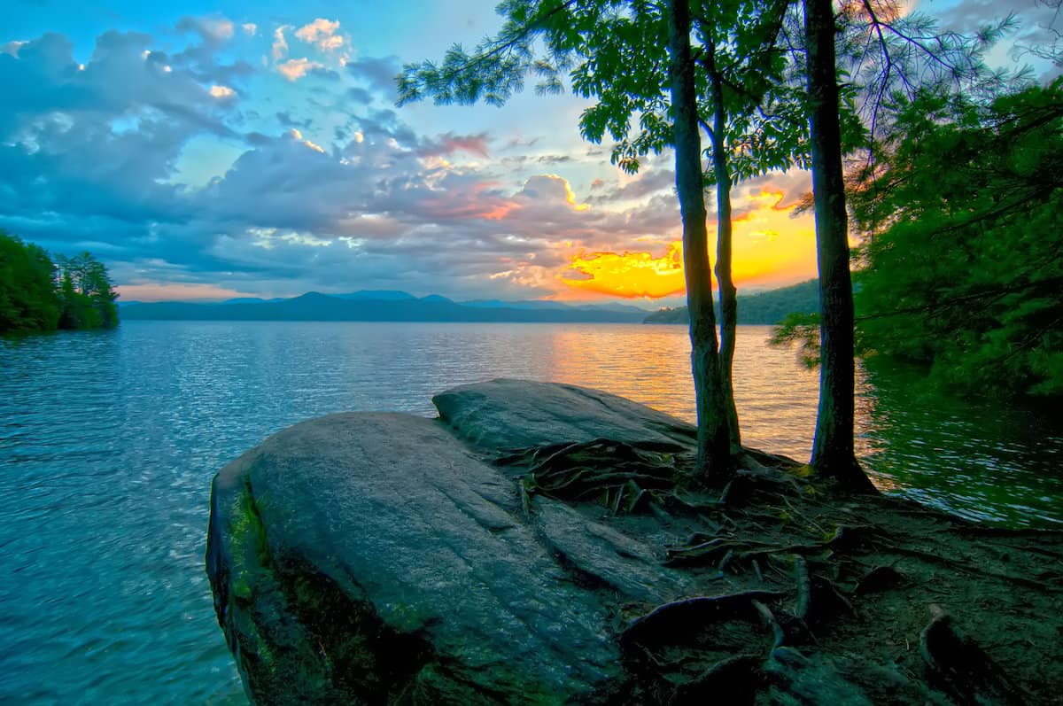 Sun low on the horizon over the calm water of Lake Jocassee, a beautiful fishing spot in South Carolina's mountains.