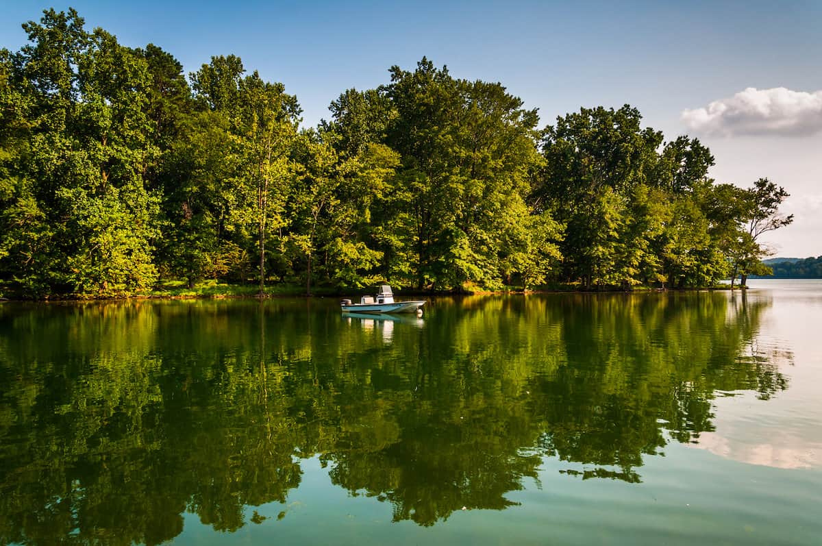 A fishing boat near the tree-line shores of quiet Loch Raven Reservoir in Maryland.