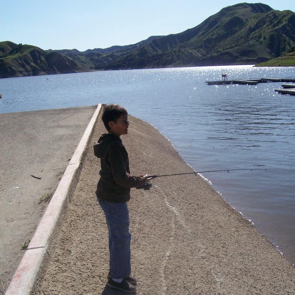 Boy fishing from the edge of a boat launch at Lake Piru, one of Southern California's best fishing lakes.